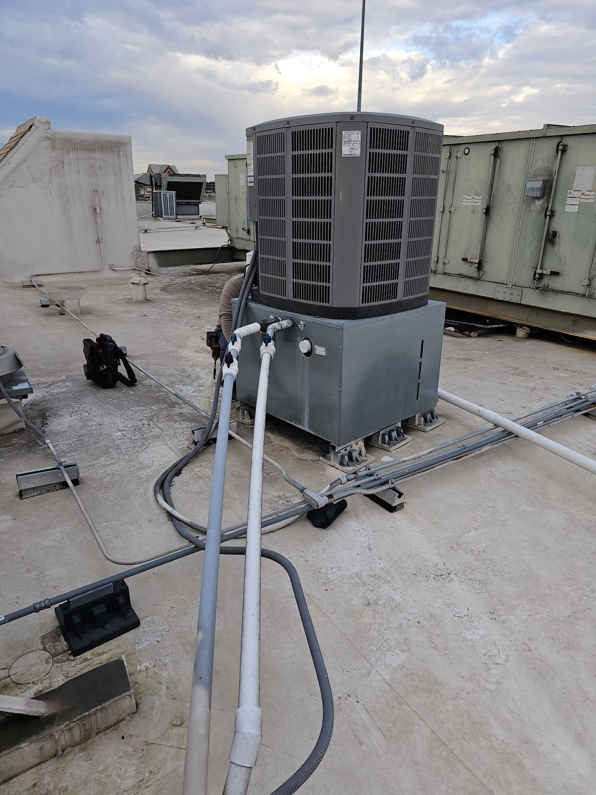 Rooftop condenser connected to gauges during a repair