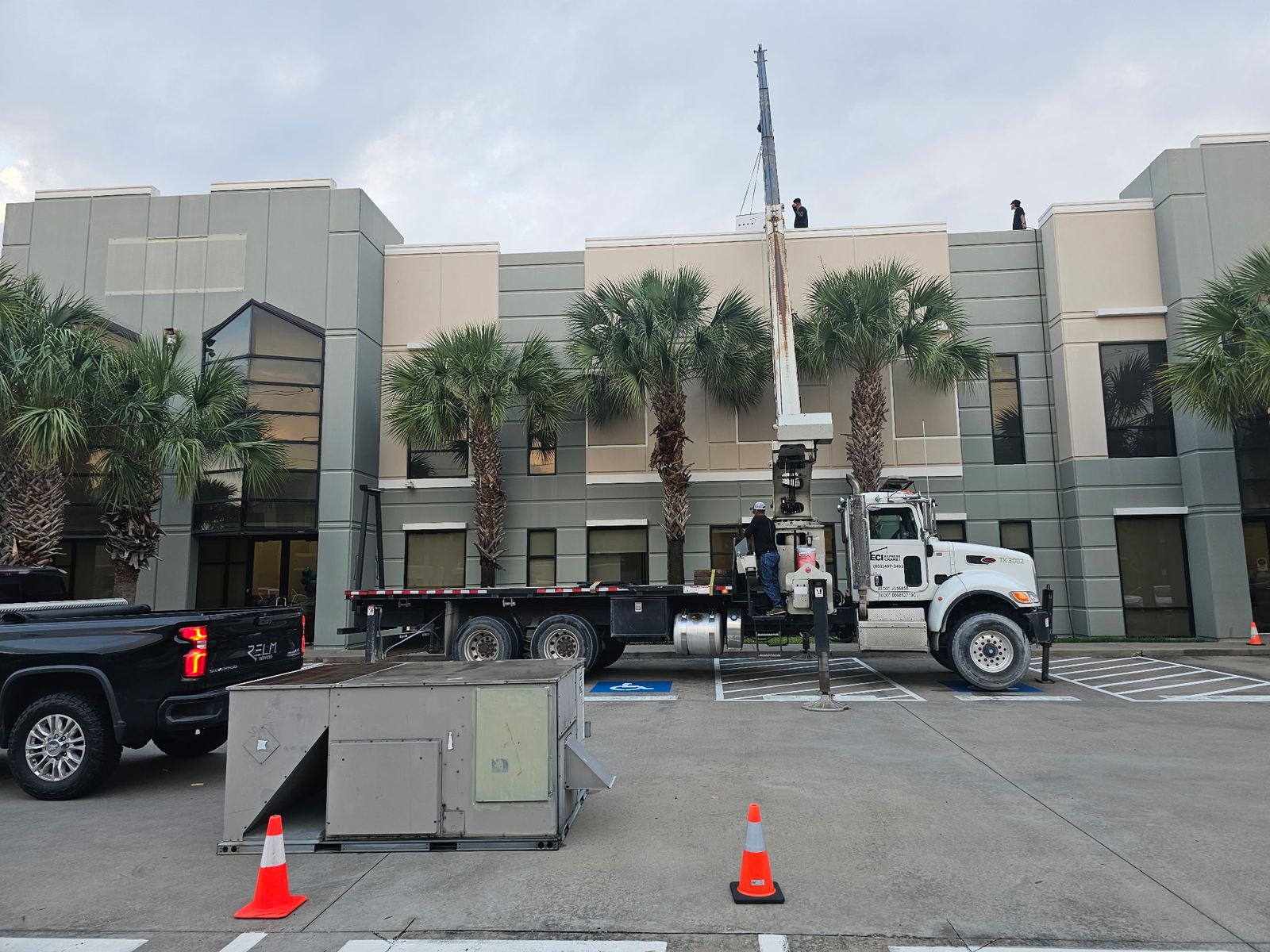 Crane setting new HVAC equipment on a Houston office building